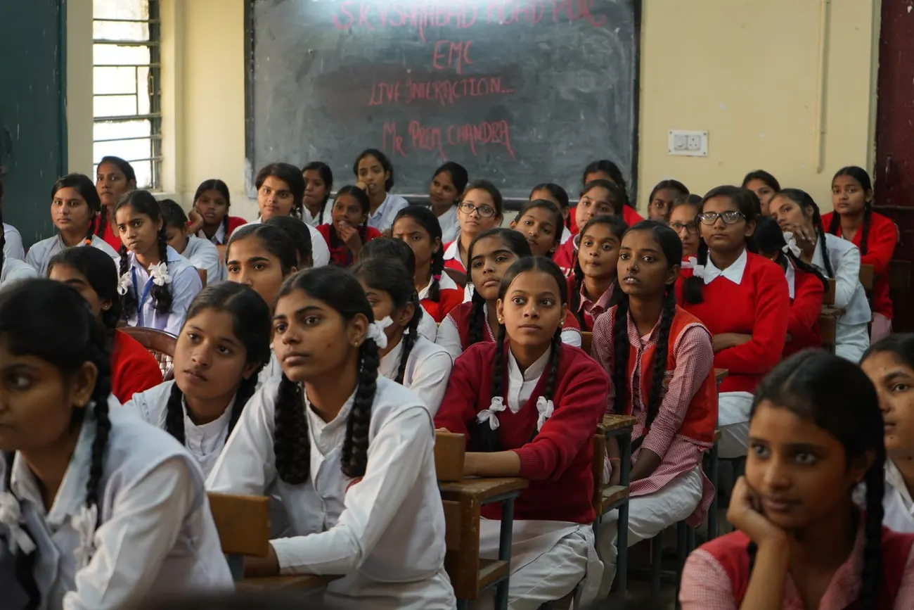 Schoolgirls in white uniforms listening attentively in class