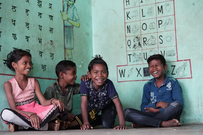 Children laughing together beside an alphabet wall